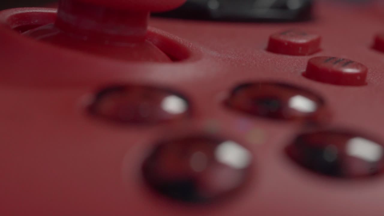 Slow Macro and closeup on red game console controller with joystick and slowly sliding over shiny buttons