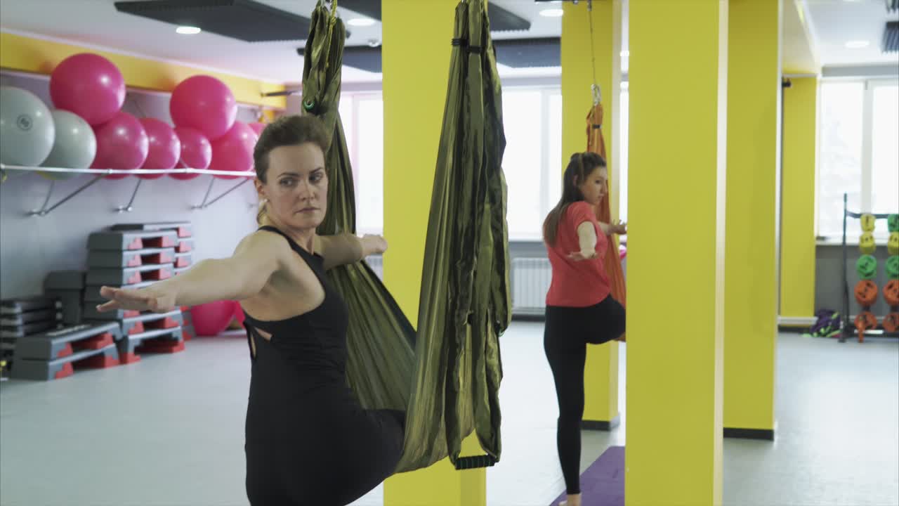 Women practicing aerial yoga in a fitness studio