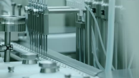 medical drug glass ampoule vaccine vials mass on production line in modern laboratory pharmaceutical factory. machine puts bottle caps on ampoules moving on pharmaceutical conveyor belt.