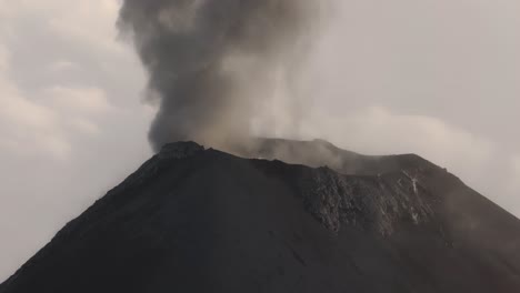 cratere vulcanico attivo con un pennacchio di cenere vulcanica che si eleva nell'aria