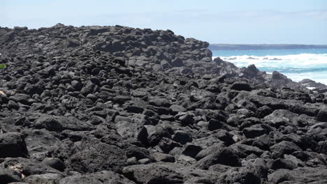 Schwarze-Lavafelsen-In-Der-Nähe-Von-Las-Grietas-Mit-Brechenden-Meereswellen-Im-Fernen-Hintergrund-Auf-Den-Galapagosinseln