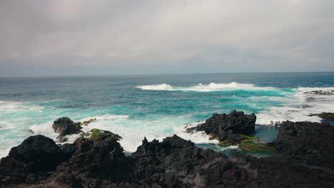 Slow-motion-shot-of-rough-ocean-waves-crushing-against-the-volcanic-rocky-coastline