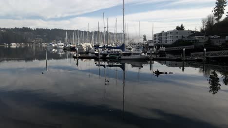 Glass-like-water-reflecting-the-sky-and-Fog-shrouded-Mount-Rainier-over-Gig-Harbor,-aerial-track-up