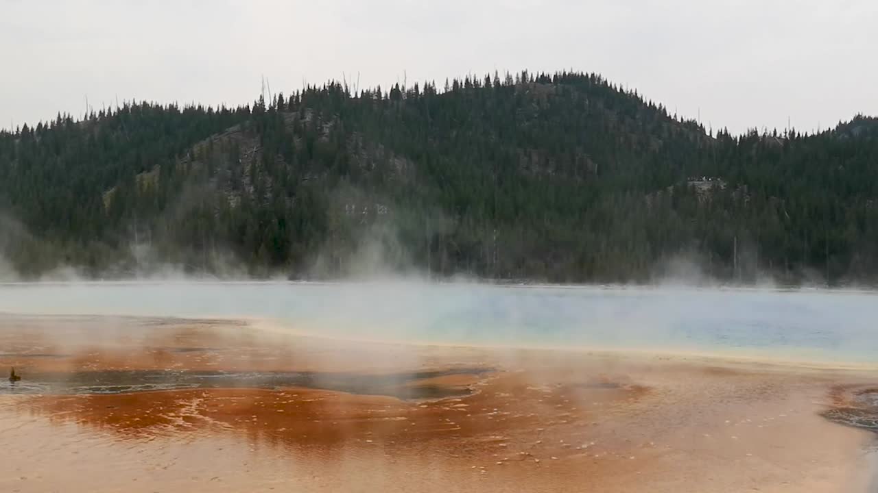 gran manantial prismático con vapor en el aire y paisaje montañoso en el parque nacional de yellowstone wyoming, estados unidos
