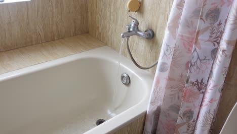 water running into a bathtub with a shower curtain