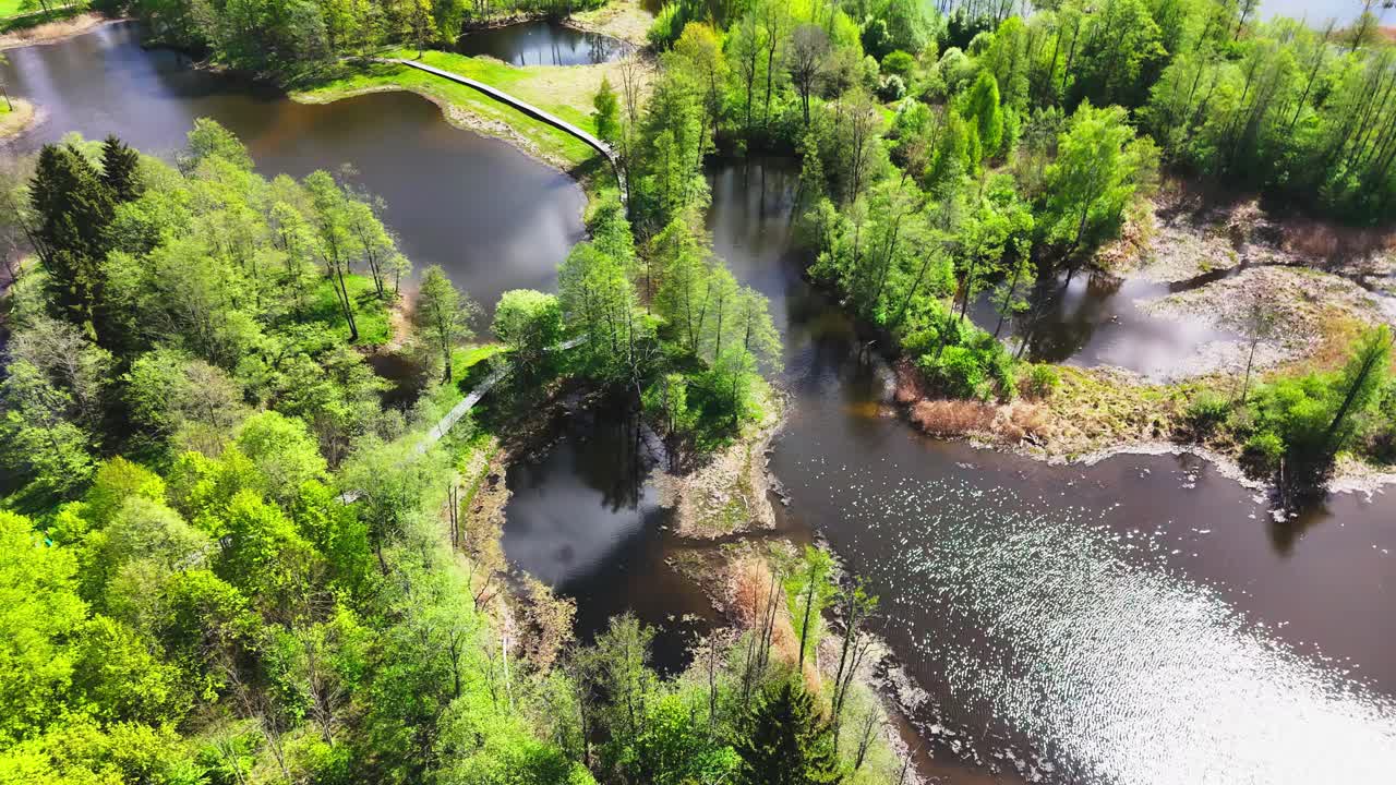 Regionální park Biržai, Litva – Malebný pohled na klikaté mosty, třpytivé vody krasového jezera a živou zelenou vegetaci – Kruhový záběr dronem