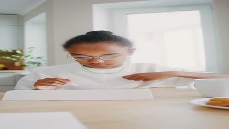 girl studying on a digital tablet in a kitchen