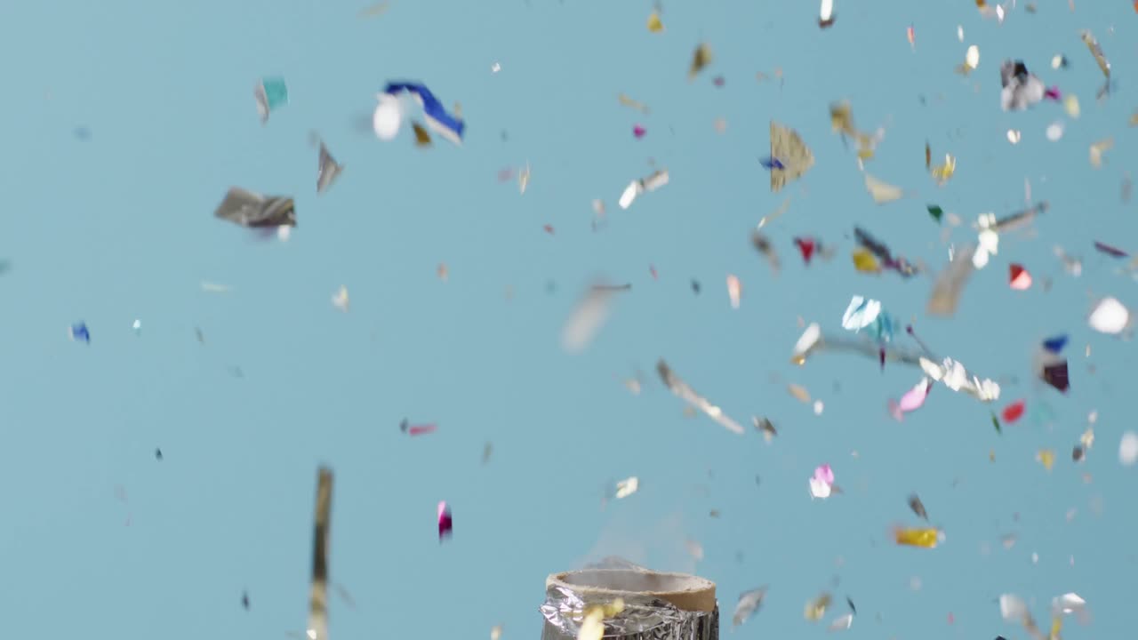 video de la explosión de la fiesta popper y la caída de confeti sobre fondo azul