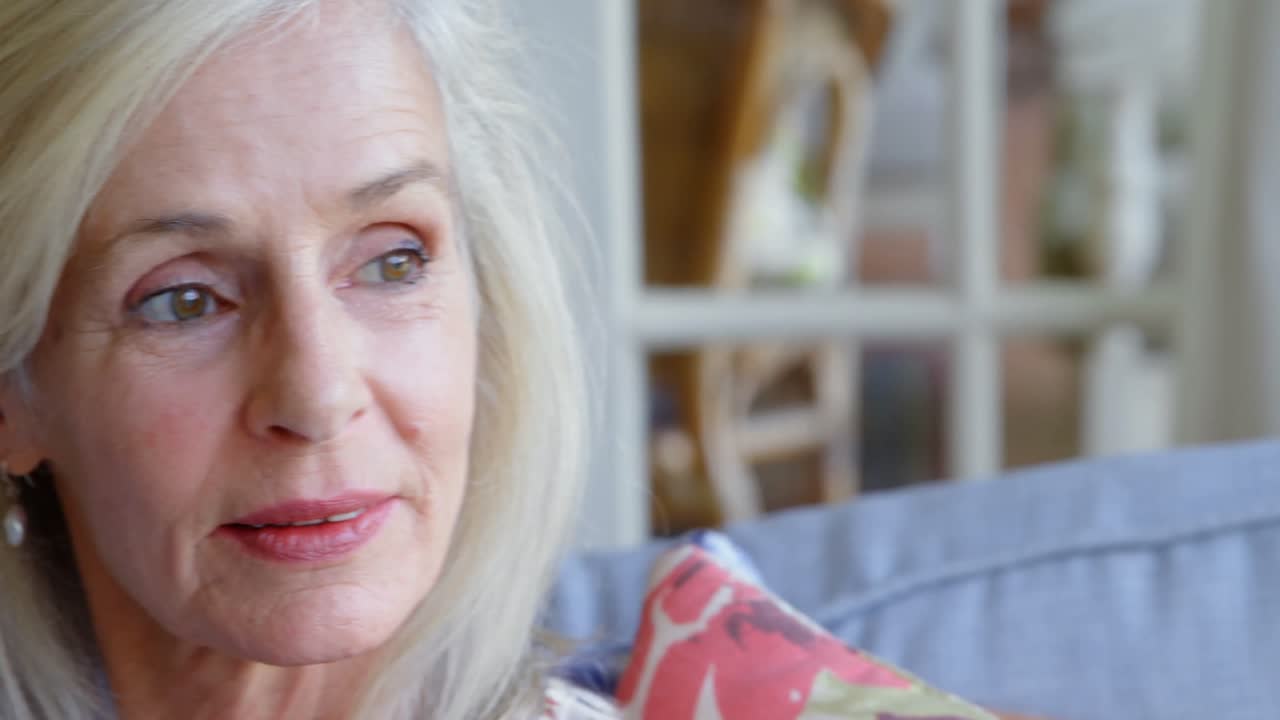 mujer mayor pensativa sentada en el sofá en casa 4k