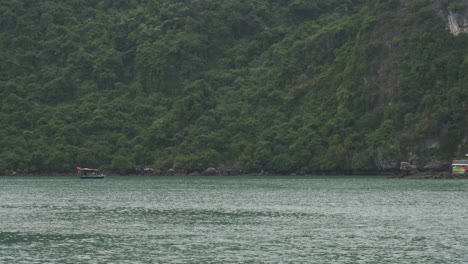 Vintage-Wooden-Junk-Boat-in-the-distance-and-floating-village-In-The-Seascape-Of-Ha-Long-Bay-In-Vietnam