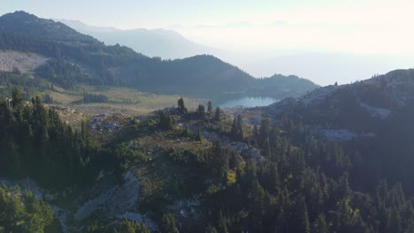 Erstaunliche-Luftaufnahme-Auf-Dem-Berggebräu-Mit-See-Und-Dunstigem-Berghintergrund-In-Kanada-4k