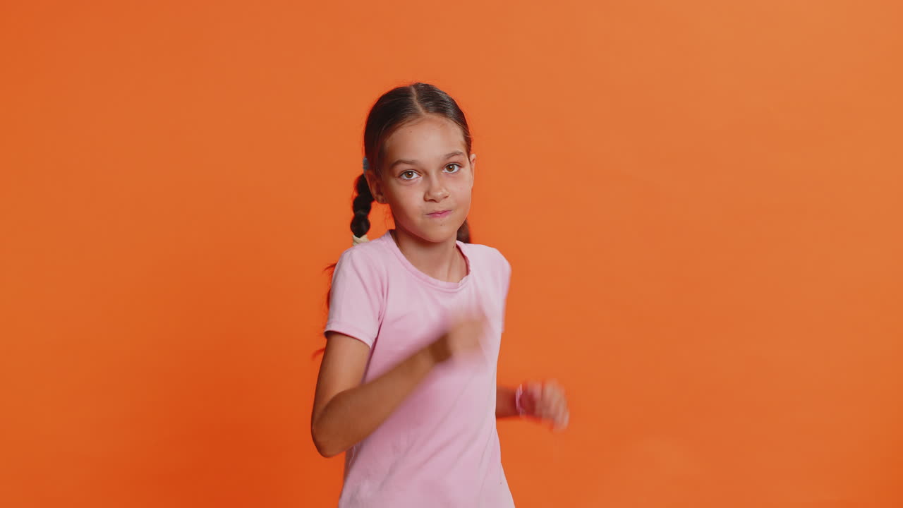 Happy child girl having fun dancing moving to rhythm dabbing raising hands making dub dance gesture