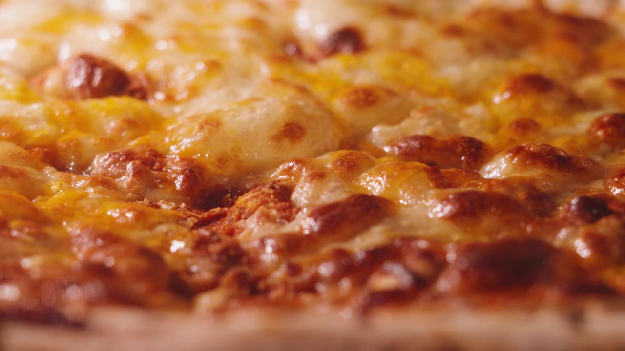 Primo piano di mozzarella che bolle lentamente e in modo soddisfacente su una classica pizza Margherita con formaggio e pomodoro e bordo ripieno, che cuoce in forno caldo. 4K