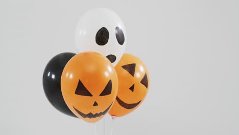 caras aterradoras impresas un montón de globos de halloween contra un fondo gris