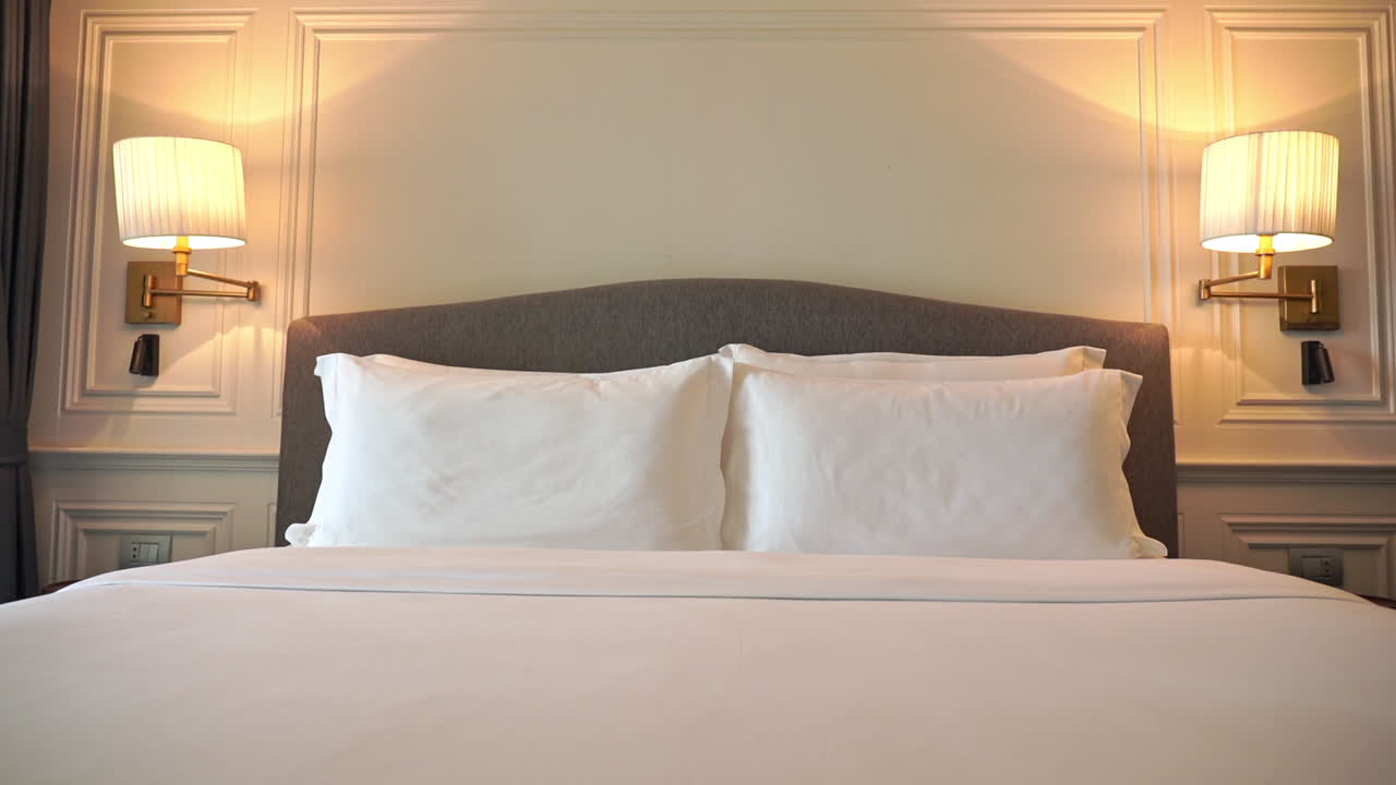 Gerakan kamera menunduk pada tempat tidur hotel yang baru dirapikan.