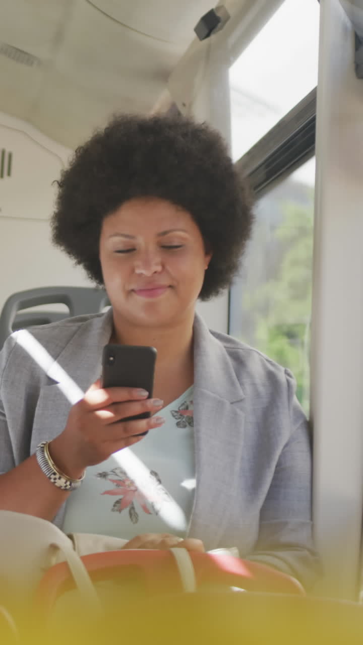 Happy plus size biracial woman using smartphone in bus