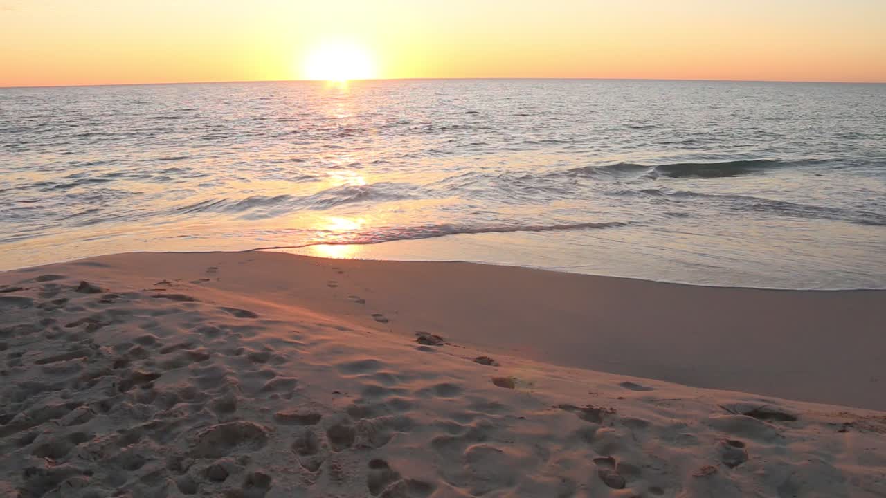 Beautiful Golden Sunset Over Ocean With Gentle Waves Lapping On Beach