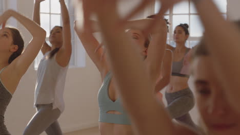 yoga class healthy caucasian woman practicing warrior pose with group of beautiful women enjoying healthy lifestyle exercising in fitness studio training at sunrise