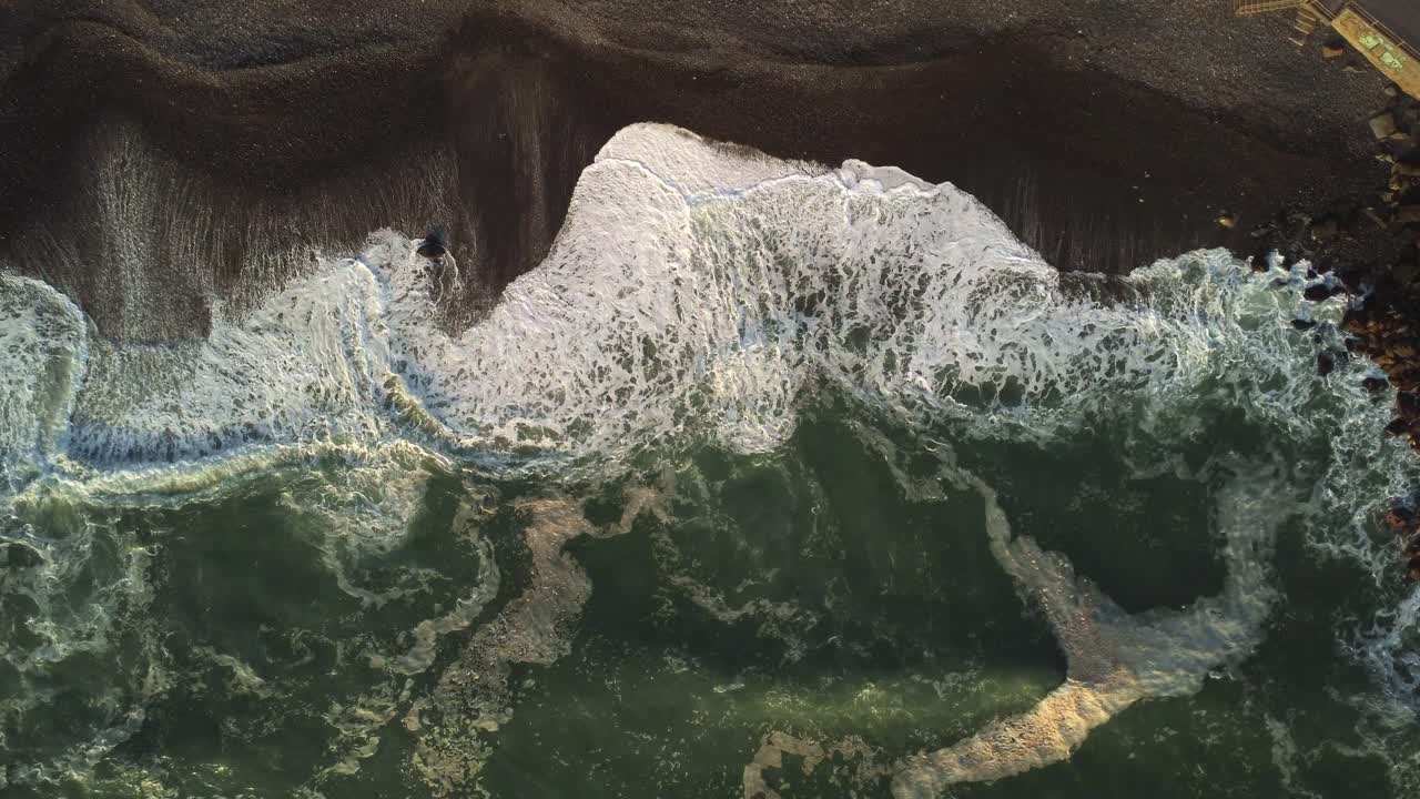 Aerial view above waves crashing a beach on the Costa Verde coast of Miraflores, Lima - top down, drone shot