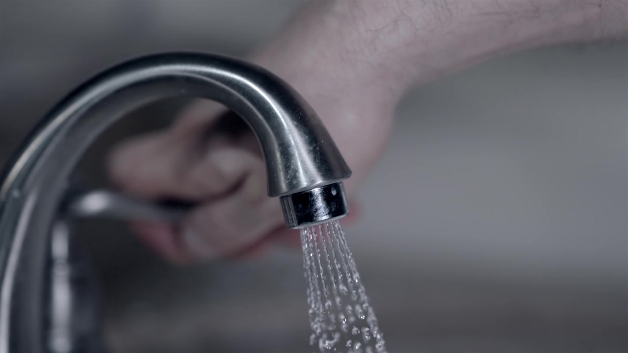 Household water conservation concept with running kitchen sink tap