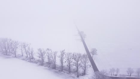 a country landscape covered with snow and shrouded in thick fog