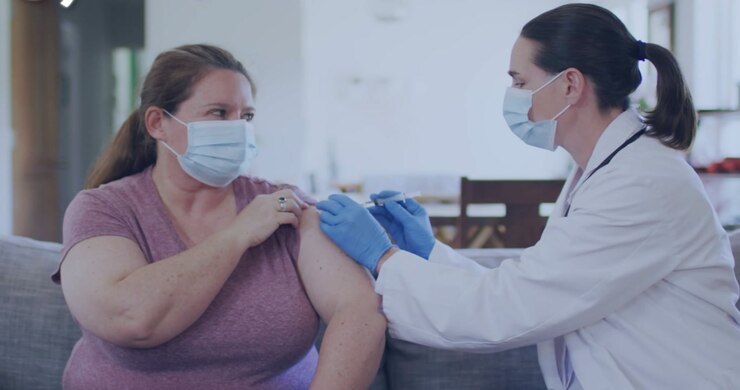 Patient rolling up sleeve, clinician preparing syringe, aligning needle, injecting arm for vaccine