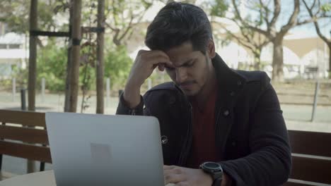 joven serio pensando y trabajando con una computadora portátil