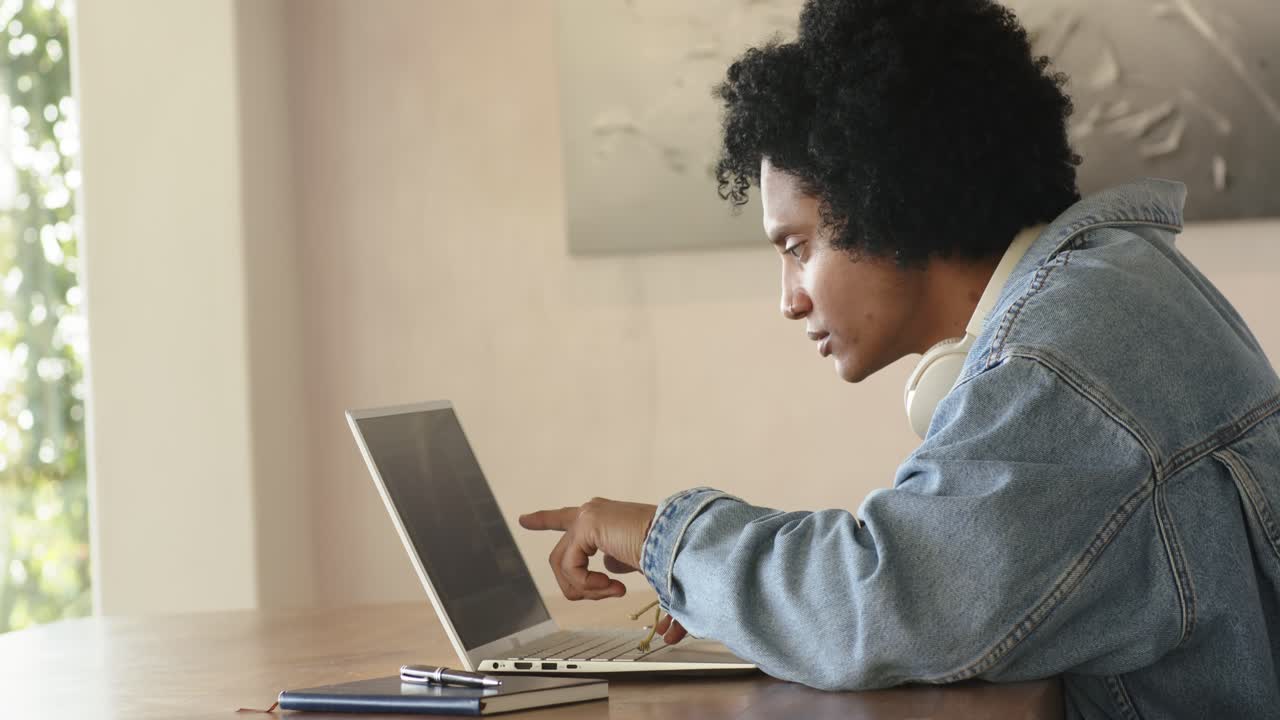 Mid-adult man powering on laptop beside window tapping display sipping coffee while analyzing data