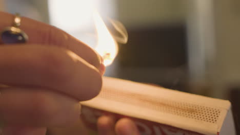 close up of a woman's hand attempting to light a wooden match on a match box and fails, she tries again