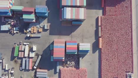 aerial footage of a large truck moves a small package on its trailer while a forklift loads an empty container