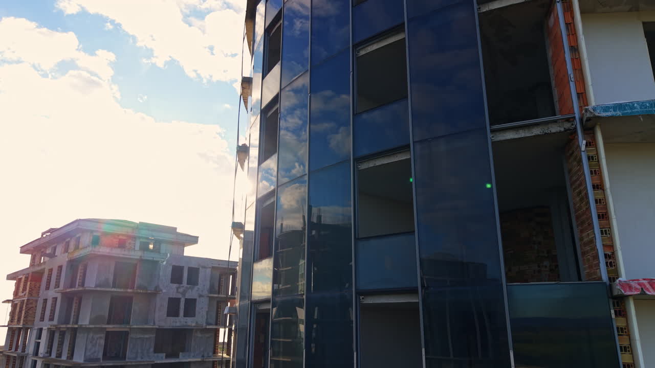 Obras con varios edificios en construcción. A lo largo de la fachada de cristal del rascacielos en ascenso