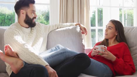 Video-Eines-Glücklichen-Kaukasischen-Paares,-Das-Auf-Dem-Sofa-Sitzt-Und-Kaffee-Trinkt