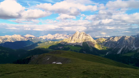 aerial view flying across lush grassy meadow overlooking spectacular rugged dolomites landscape