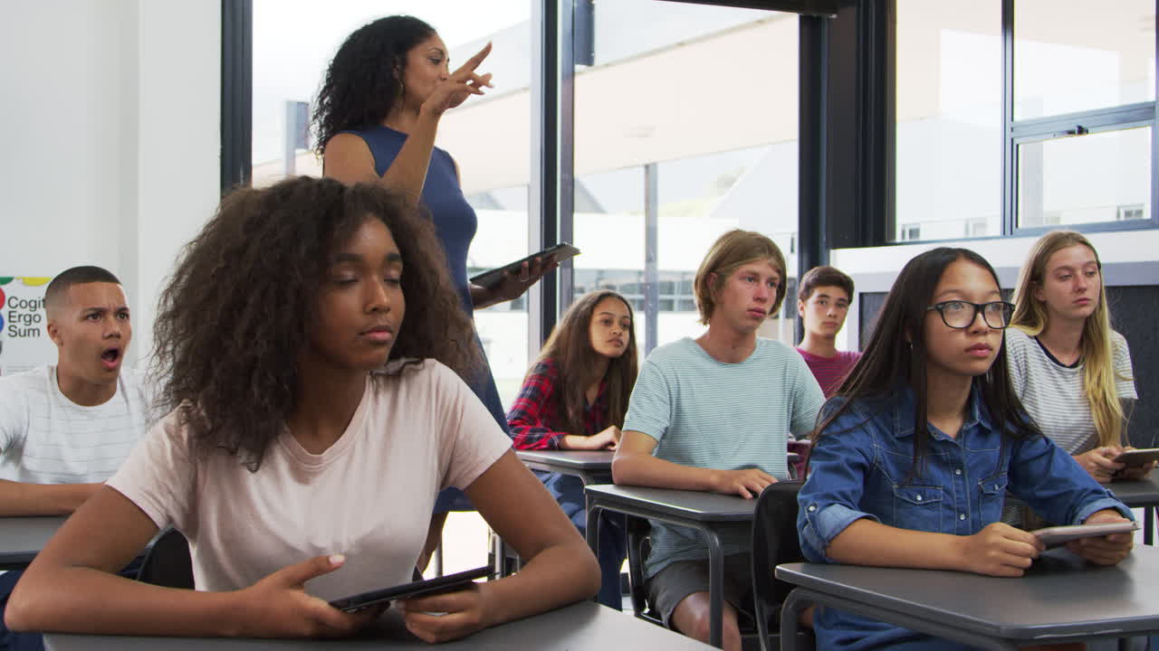 Teacher addressing pupils from the back of her high school class