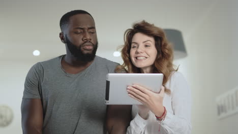 young couple standing at living room with tablet together.