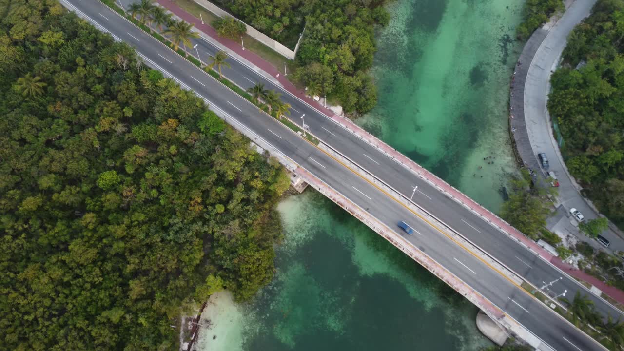 Drone shot panning over the Punta Nizuc bridge in Cancun Mexico over the Nichupte lagoon surrounded by a mangrove forest and emerald green river canal