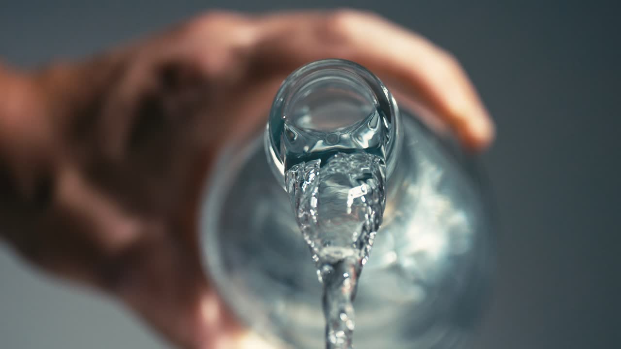 유리 병에서 끊임없이 흘리는 건강한 은 물의 흐름, 더 나은 건강을 위해 수분을 유지하는 것의 중요성, 치료, 고속, 느린 동작, 클로즈업