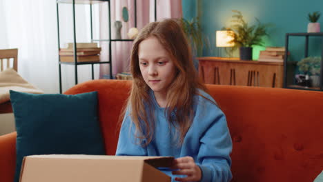happy young child kid girl unpacking delivery parcel opening cardboard box receiving purchase gift