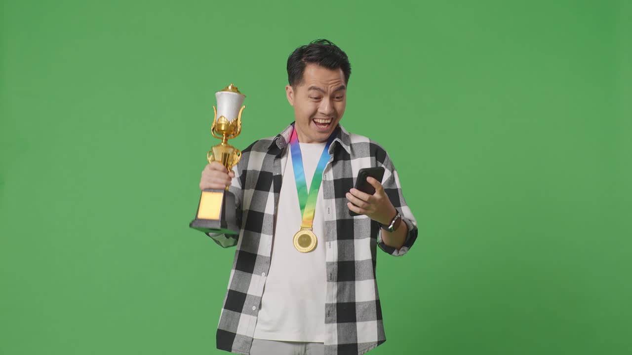 트로피와 스마트폰으로 승리를 축하하는 남자