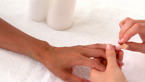 beautician filing female clients nails at spa beauty salon