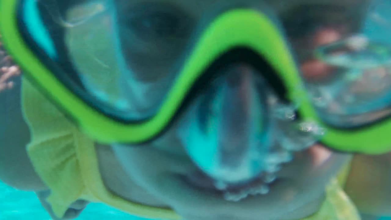 Little girl swims underwater in an underwater panoramic mask. A child snorkels. Bubbles surround the baby on all sides.