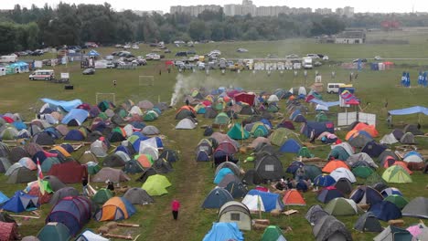 aerial view of multi-colored tents pitched in a field at a music festival with people walking around
