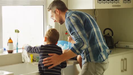 padre y hermanos limpiando el fregadero de la cocina 4k