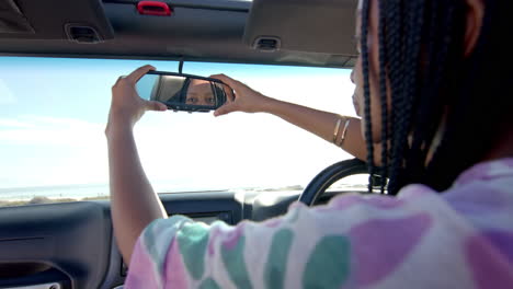 Una-Joven-Afroamericana-Ajusta-El-Espejo-Retrovisor-De-Su-Coche-En-Un-Viaje-Por-Carretera