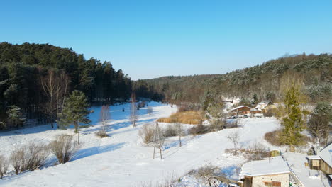 White-snow-covering-fields-and-backgardens-between-a-streched-forest-on-a-bright-sunny-winter-day