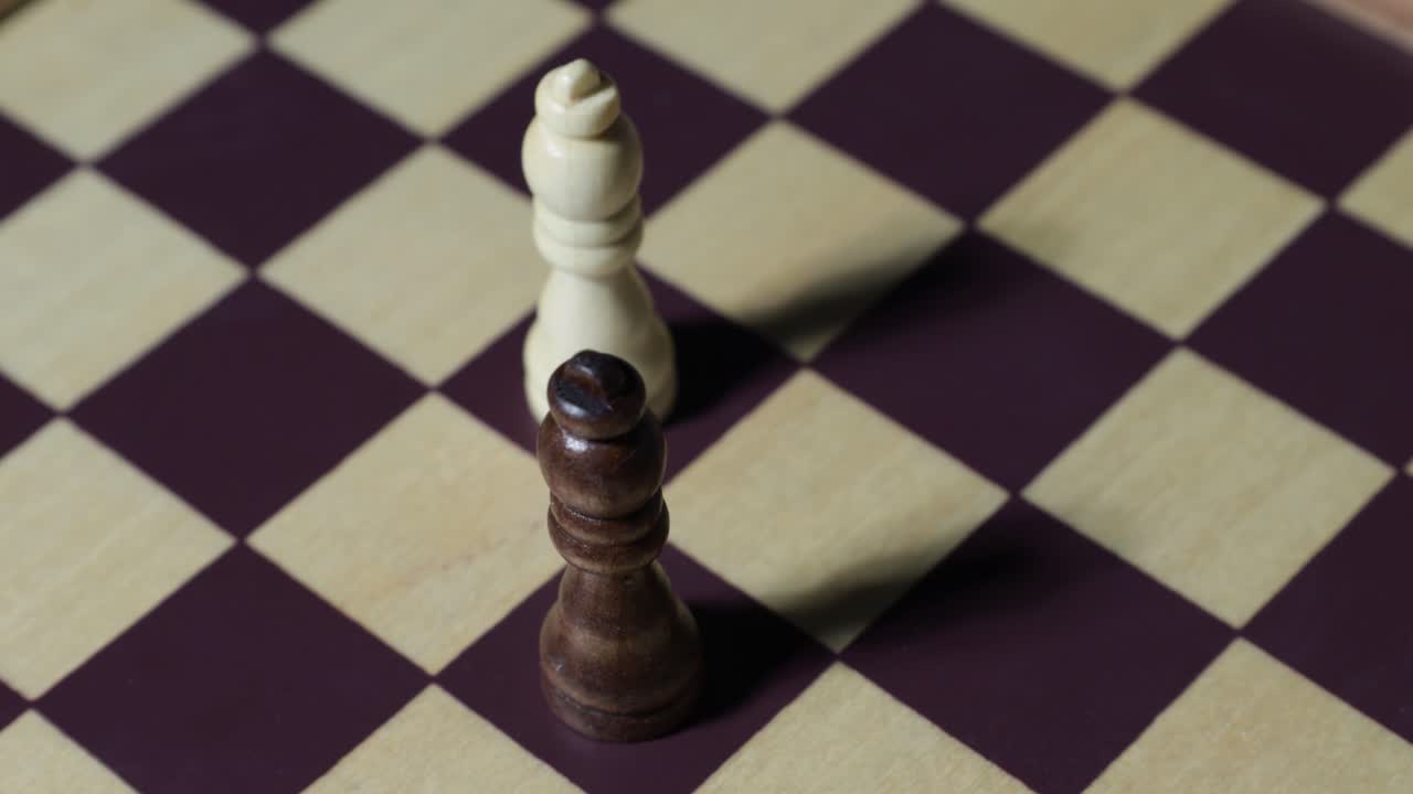 Rotating shot of two chess queens with shadows on chessboard