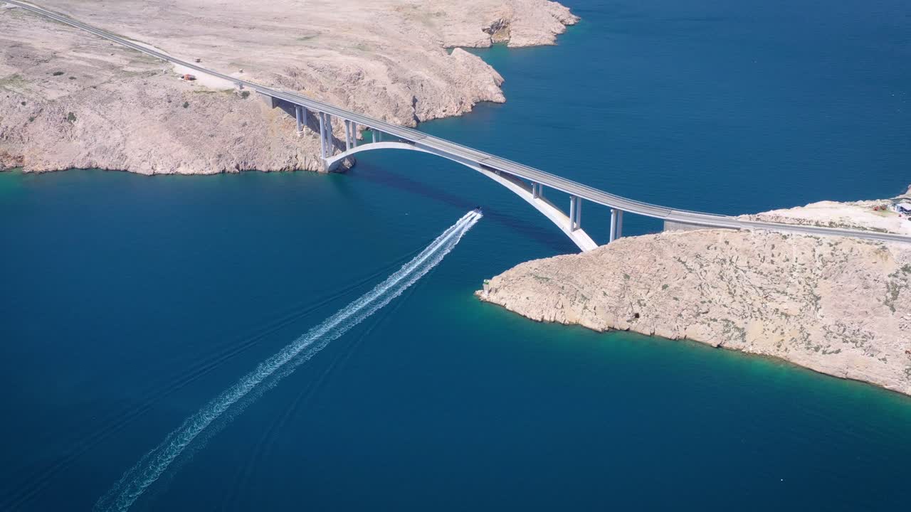 Vista aerea di una barca che si muove attraverso il canale sotto il ponte di Pag, Croazia. Allontanamento