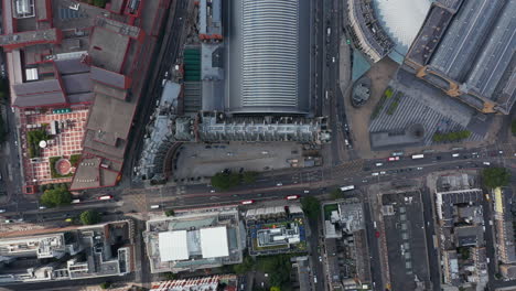 Aerial-birds-eye-overhead-top-down-ascending-view-of-traffic-on-multilane-road-in-street-in-front-of-St-Pancras-train-station.-London,-UK