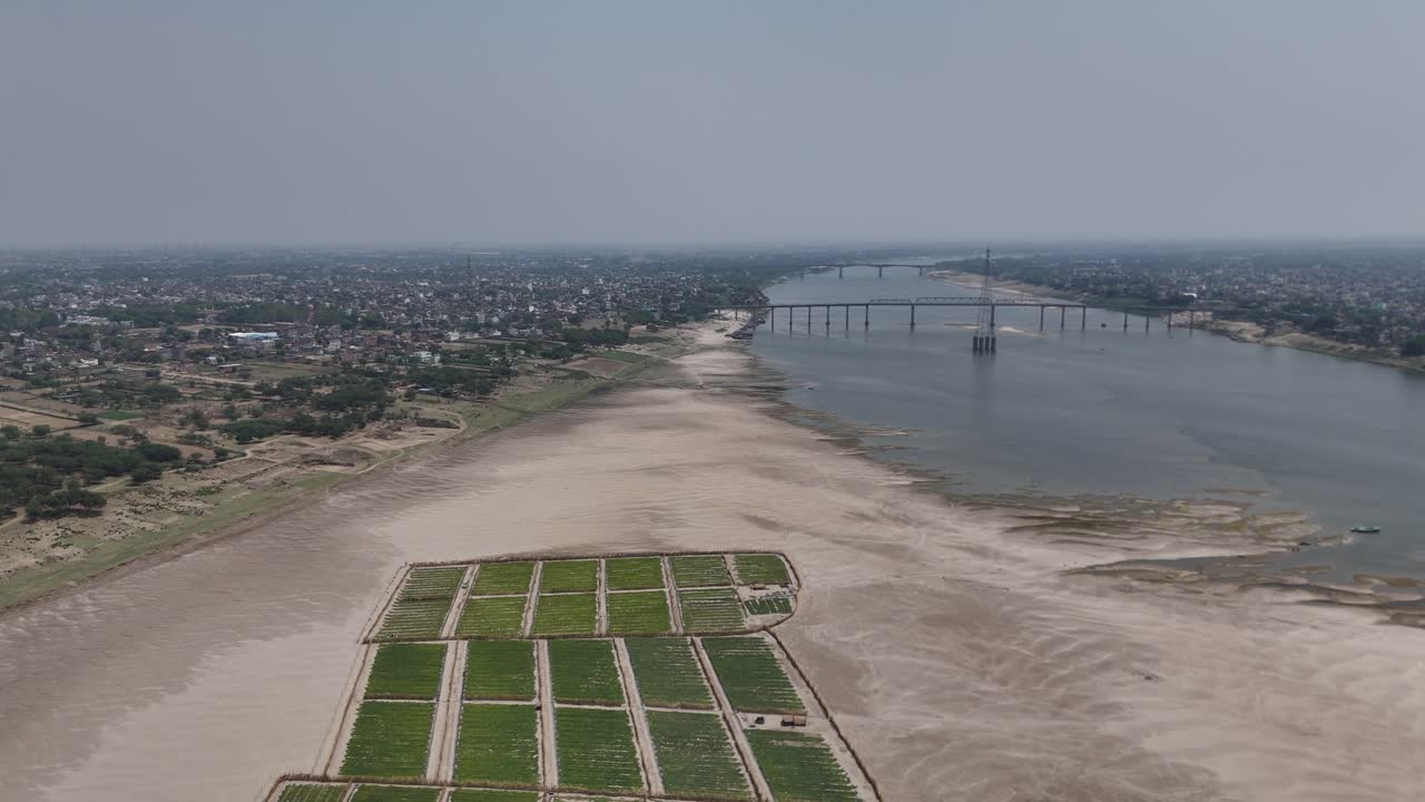 Aerial footage capturing the evening glow over Varanasi, as the sun sets behind the densely packed neighborhoods and historic temples along the Ganges.