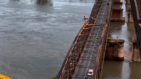slow motion aerial orbit of the historic iron ponte di ferro bridge connecting lombardy and emilia-romagna, with its lattice steel structure crossing the wide po river